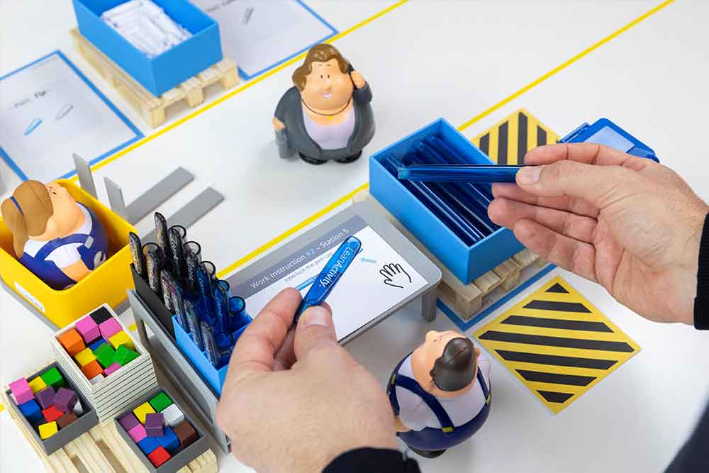 Hands assembling pens at a LeanActivity Factory Game workstation